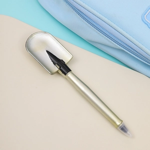 Macro shot of creative shovel-shaped ballpoint pen in champagne gold with clear cap
