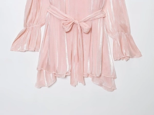 Détail de la robe rose brillante avec poignets à volants et ceinture nouée en satin