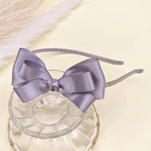 Detail of elegant purple satin bow headband resting on a glass decorative accessory