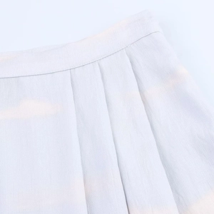 Gros plan sur la jupe mi-longue plissée bleu clair montrant la texture du tissu fin