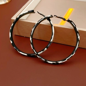 Detail of round leopard pattern earrings on leather texture with high-end vintage style