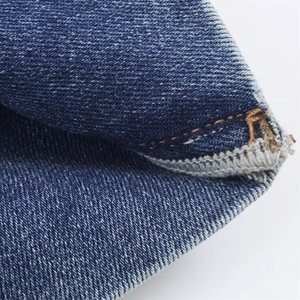 Gros plan détaillé du tissu denim bleu montrant le tissage sergé et la couture double renforcée
