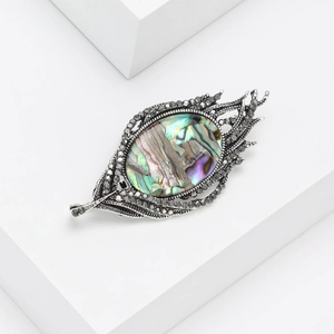 Elegant feather brooch featuring a vibrant oval abalone shell with dark rhinestone accents