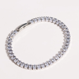 Macro shot of silver tennis bracelet featuring sparkling clear zircon stones on white background