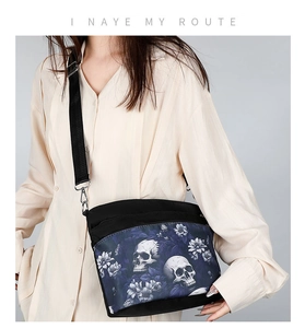 Détail du sac bandoulière avec imprimé crâne et fleurs mauves sur tissu oxford noir