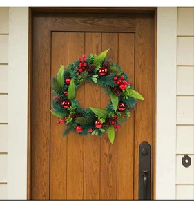 Detailed view of Christmas wreath with red ornaments and pine cones on a wooden door