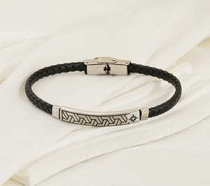 Detail eines schwarzen Lederarmbands mit gravierter Edelstahlplatte und Magnetverschluss