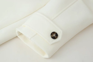 Detailed macro view of ivory wool coat cuff with tortoise shell button and fine stitching