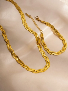 Macro detail of the gold braided snake chain texture and lobster clasp on silk background