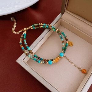 Dettaglio di un bracciale a doppio strato con perle di turchese, pietre e oro