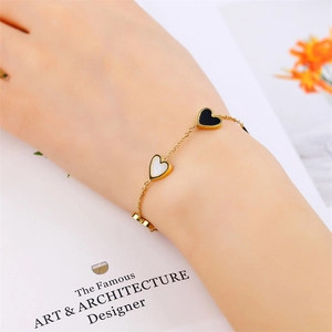 Elegant titanium steel bracelet with gold chain and black and white heart charms on model
