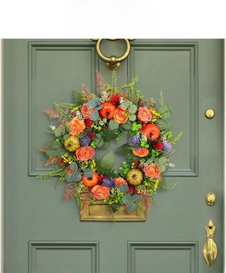 Detail view of autumn wreath with pumpkins and orange roses on a green door