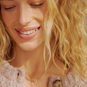 Close-up of minimalist heart pendant necklace in 18k gold on a woman neck