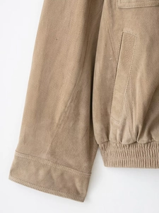Detail of suede jacket cuff and elastic hem showing high-quality stitching and texture