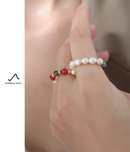 Detail of handmade natural pearl beaded ring with colorful accents on model hand