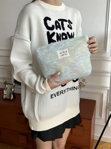 Plush rainbow macaron knitted makeup bag with soft fuzzy texture and brand label