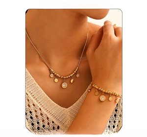 Close-up of gold stainless steel necklace and bracelet set with round Roman numeral charms