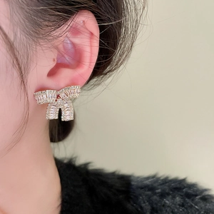 Dettaglio di orecchini a fiocco con zirconi scintillanti indossati per un look raffinato