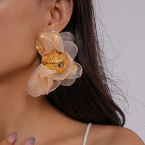 Gros plan de boucles d'oreilles fleur en mousseline beige avec centre doré texturé