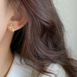 Elegant gold bow earrings with a knotted ribbon design shown on a model for daily wear