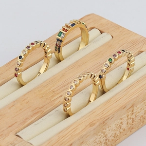 Close-up of four gold rainbow rings with colorful cubic zirconia on a wooden display