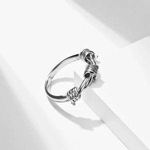 Polished titanium steel knot ring with thorn design on minimalist white stone base