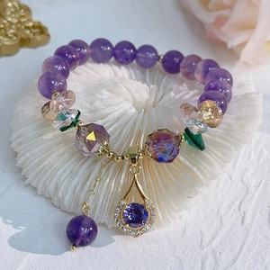 Close-up of purple amethyst bead bracelet with gold accents on white coral stone