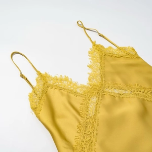 Detailed view of yellow satin camisole with delicate lace trim on V-neckline