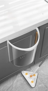 Detail of wall-mounted translucent grey kitchen trash bin hanging on cabinet door