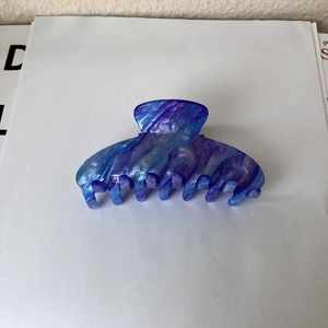 Close-up of star-patterned marble hair claw clip with blue and purple glitters