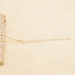 Minimalist 18K gold plated pearl necklace with gradient white beads on a textured background