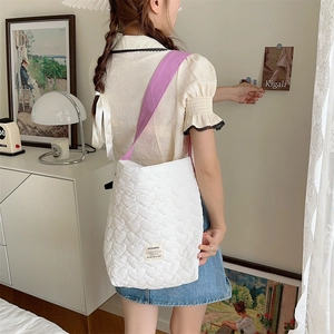 Close-up of white heart-quilted tote bag featuring a vibrant purple shoulder strap
