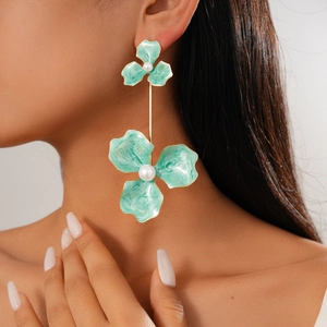 Close-up of bohemian green enamel flower earrings with pearls on female model