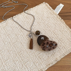 Détail du pendentif cœur en peluche léopard avec pompon sur collier argenté