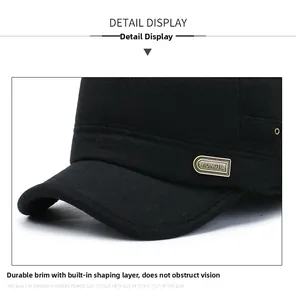 Detail of the thick wool flat top cap featuring reinforced brim and gold metal logo