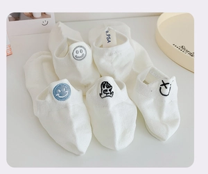 Detail of white cotton low cut socks with cute embroidered smiley faces on the heel