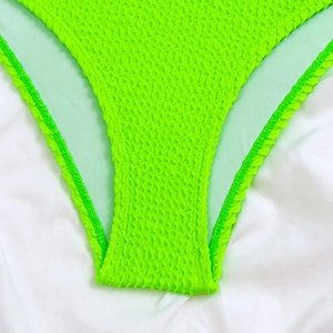Detail of neon green crinkle fabric on swimsuit bottom with textured honeycomb pattern