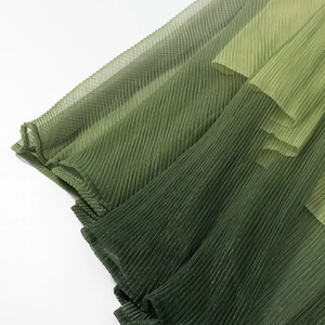 Detailed macro view of green gradient pleated fabric with soft shimmer and layered texture