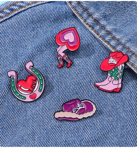 Détail de broches émaillées botte de cowboy rose et fer à cheval sur tissu en jean