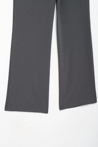Detailed view of the dark grey suit pants leg showing high-quality drape and fabric texture