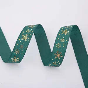 Close-up of dark green grosgrain ribbon with festive gold snowflake patterns and ribbed texture