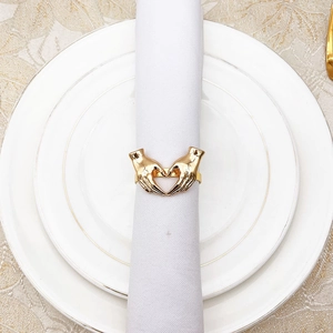 Close-up of golden heart-shaped napkin ring on white fabric for elegant table setting