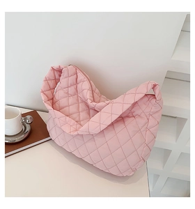 Detailed view of a pink quilted crescent bag styled on a minimalist white table setup