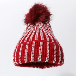 Detail of red knit hat with rows of iridescent rhinestones and a fluffy pom-pom