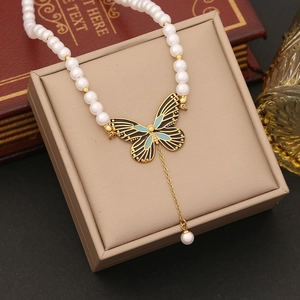 Collier de perles tendance avec pendentif papillon doré et détails en émail bleu et noir