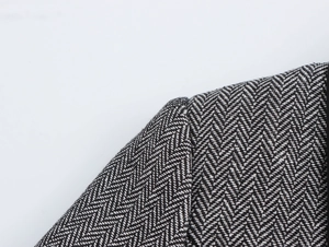 Close-up of black and white herringbone fabric texture and shoulder stitching detail