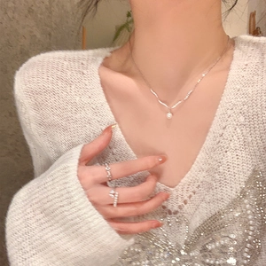 Close-up of elegant silver necklace with pearl pendant and adjustable open ring on model