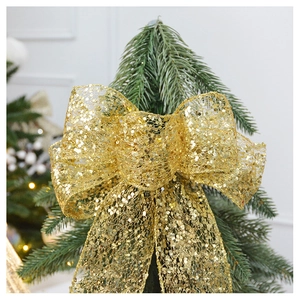 Close-up of sparkling champagne gold sequin bow topper on a decorated Christmas tree