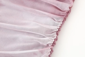 Detailed macro view showing the texture and folds of pink mesh fabric on a dress