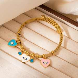 Macro detail of gold-plated twisted bangle with colorful evil eye heart charms